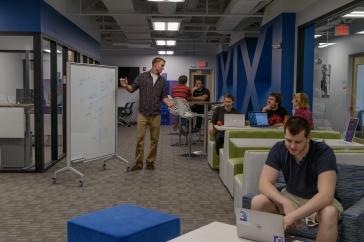 Students work at desks and a white board in a clean, modern space